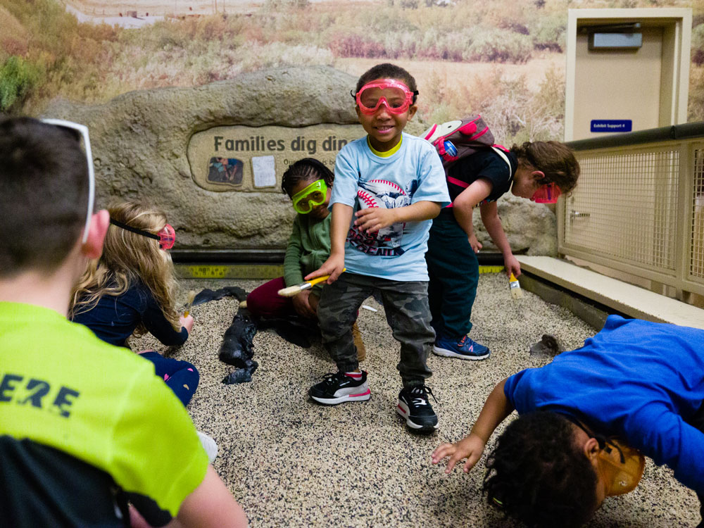 Children wearing safety goggles and digging in the mini dino dig pit inside Dinosphere.